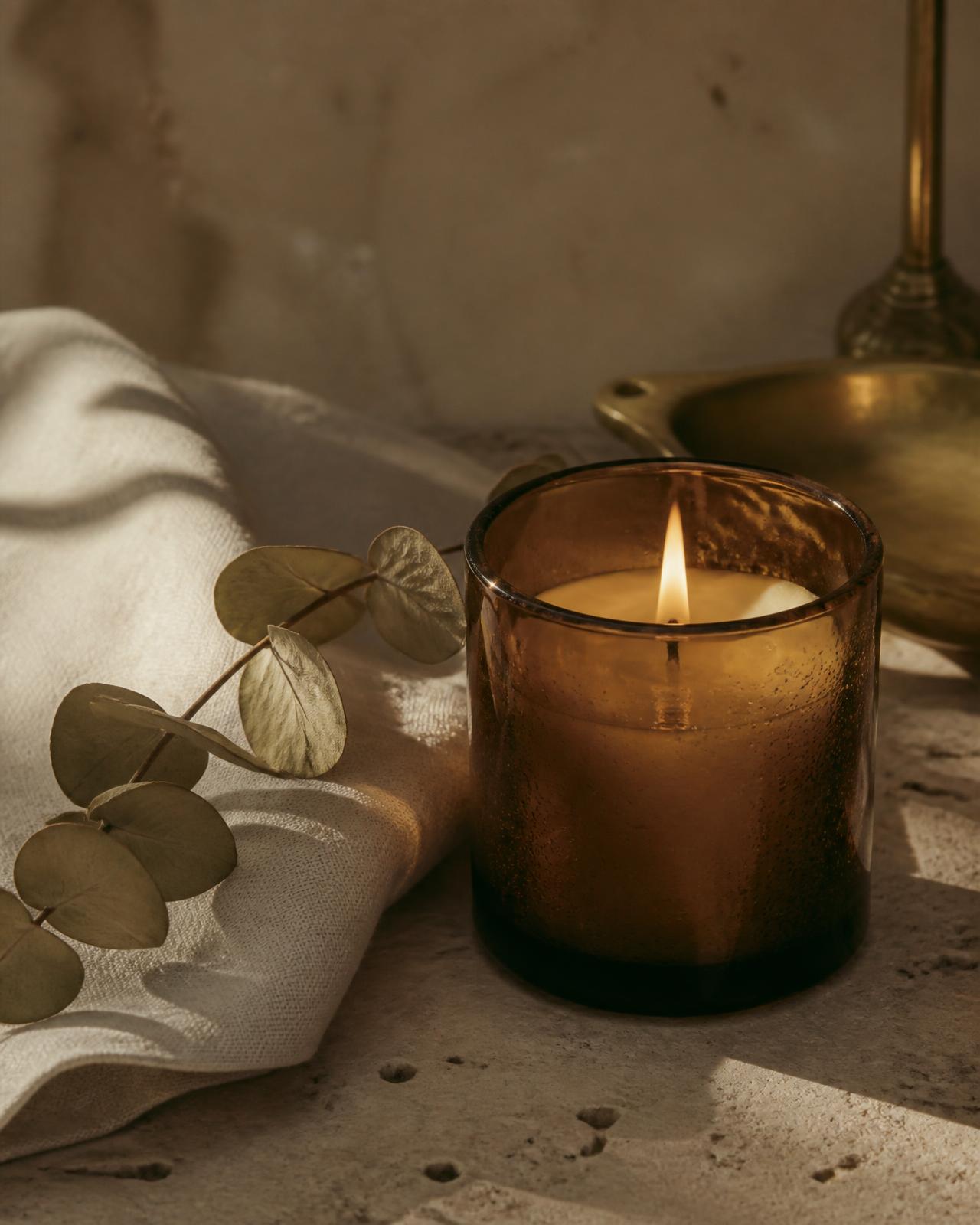 Amber scented candle on travertine with dried eucalyptus
